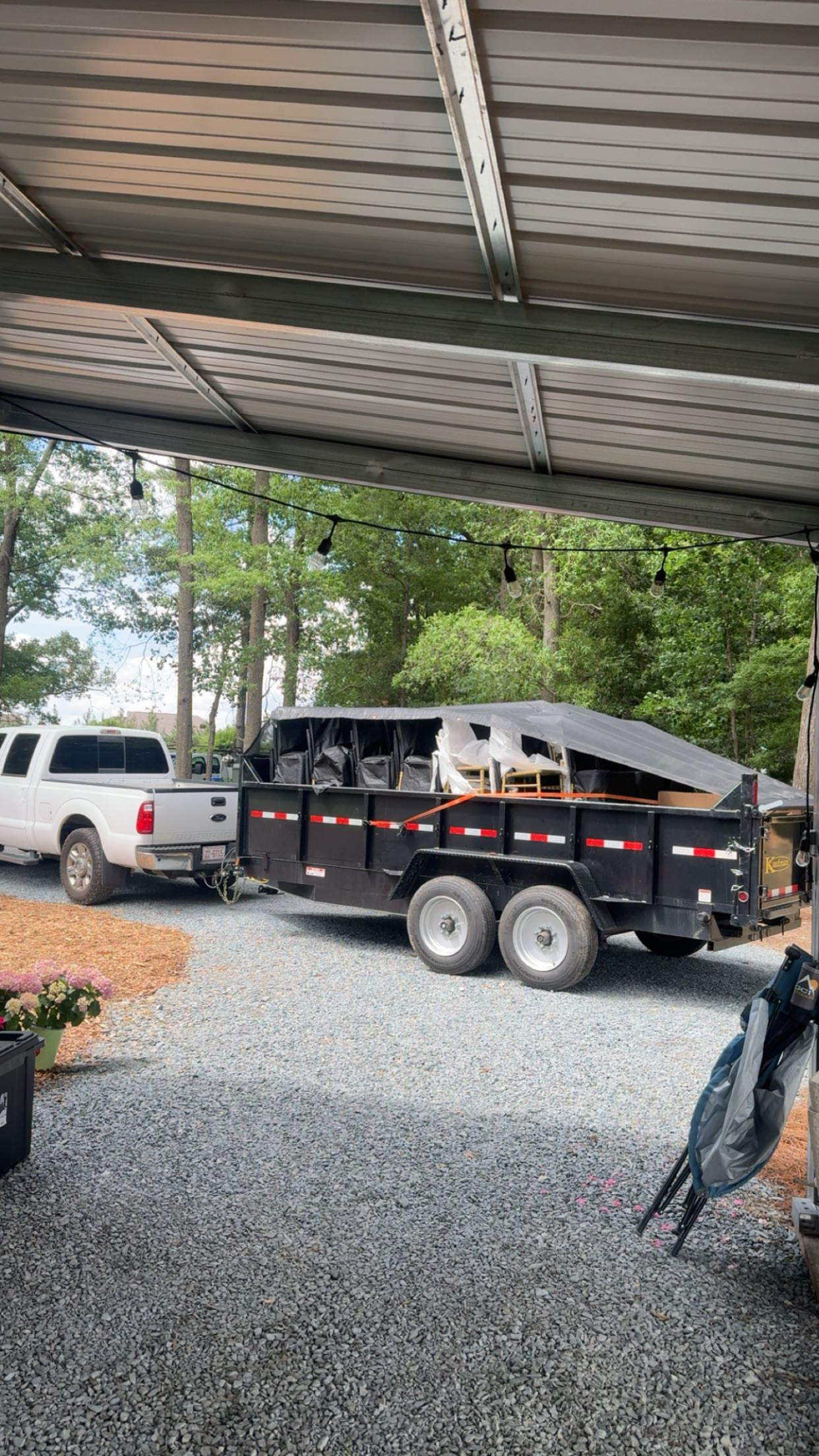 Black Kaufman dump trailer with pickup parked in driveway